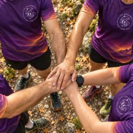 Quatre coureurs du club en maillot, mains réunies avant le départ
